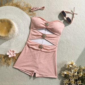 Close-up of pink textured one-piece swimsuit with sun-shaped rhinestones and cut-outs