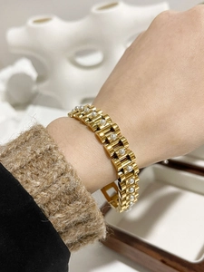 Detailed view of gold pearl watch-style bracelet on a wrist with vintage vibe