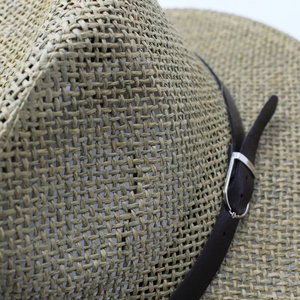 Macro detail of straw hat texture with brown leather band and silver metal buckle