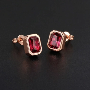 Close-up of rectangle red zircon earrings with rose gold plating on black background