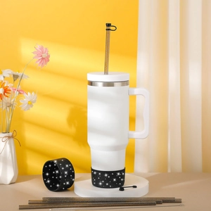 Detailed view of insulated white tumbler with glitter silicone boot, straws and brush