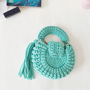Detail of mint green crochet round bag with handmade fabric yarn texture and tassel