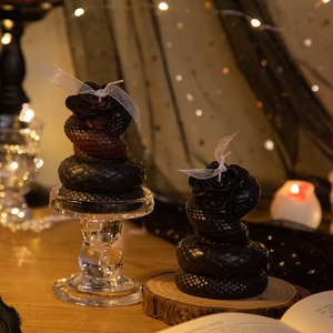 Gothic snake and rose shaped scented candles with intricate scale textures on a glass tray