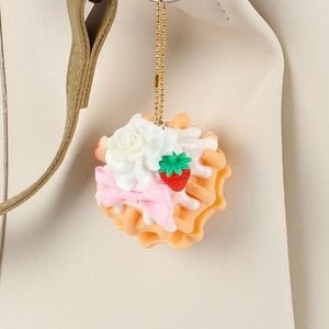 Realistic pink waffle dessert keychain with strawberry and cream on a beige leather bag