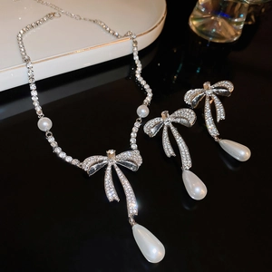 Detail of bowknot zircon necklace and teardrop pearl earrings with silver finish