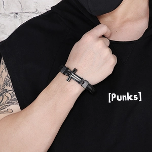 Detail of black braided leather men's bracelet featuring a metallic cross element