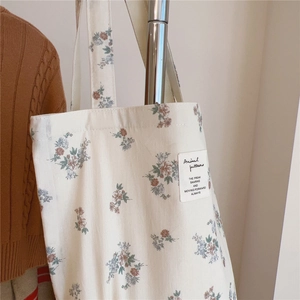 Détail du sac cabas en coton blanc avec imprimé floral vintage et étiquette artistique