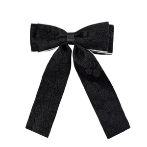 Elegant black lace bow hair clip with long ribbons and white trim on white background