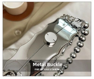 Detail view of the silver leaf-shaped acrylic evening bag with a wave pattern and beaded chain