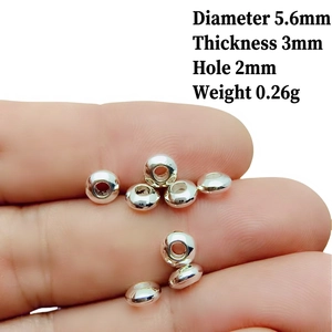 Close-up of 5.6mm silver alloy spacer beads on fingers showing small size for DIY jewelry