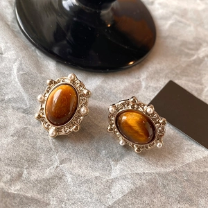 Vue détaillée de boucles d'oreilles ovales œil de tigre avec motifs dorés et perles