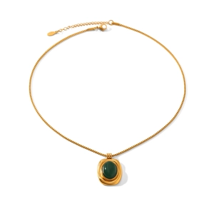 Detailed shot of a vintage gold box chain necklace with an oval emerald green gemstone pendant