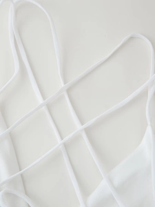 Detail view of intricate crisscross lace-up back on a white sexy backless mini dress