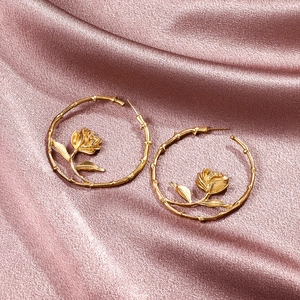 Elegant gold-tone rose hoop earrings with detailed branch texture on a silk background