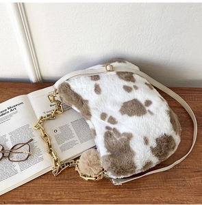 Detailed macro view of plush cow pattern tote bag with gold chain strap and soft texture