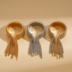 Perlenquasten-Ringe in Gold und Silber auf einem strukturierten sandigen Hintergrund