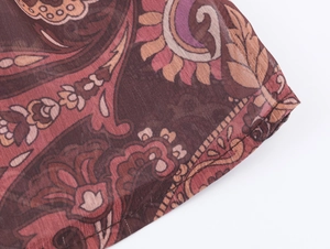Detailed close-up of paisley pattern on sheer reddish-brown bohemian chiffon fabric