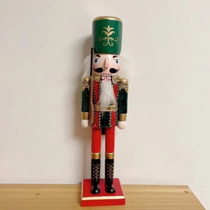 Classic wooden nutcracker soldier figure with green hat and rifle on a red square base