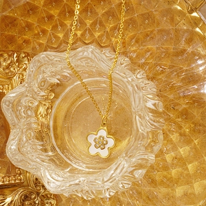 Gros plan du collier trèfle doré avec pétales en nacre blanche et cristaux au centre