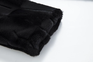 Detailed macro view of dense black faux fur texture and striped stitching on the coat sleeve