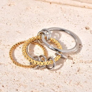 Macro detail of intertwined gold twisted and silver smooth bands on beige stone