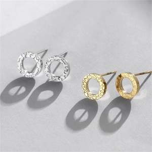 Detailed view of gold and silver round stud earrings with hammered metal texture