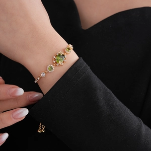 Détail du bracelet plaqué or avec cristaux verts sur le poignet d'un mannequin