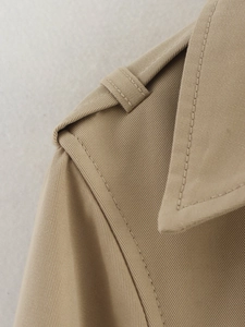 Detailed macro view of khaki trench coat epaulette and high-quality twill fabric texture