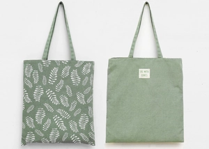 Detailed view of heavy canvas tote bags in forest green with leaf print and brand labels