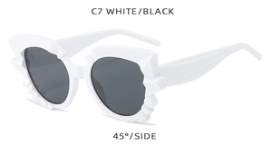 Detail view of white irregular wave frame sunglasses with black lenses from 45 degree angle