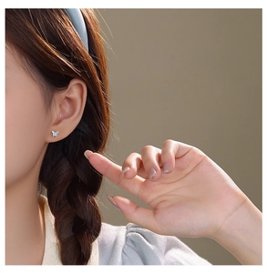 Close-up of a delicate light blue butterfly stud earring worn on a model's ear lobe