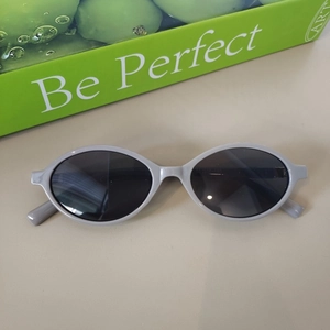 Macro shot of grey oval sunglasses with black lenses and white model specs on the temple