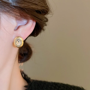 Close-up of gold oval stud earring with clear rhinestone on model for jewelry display
