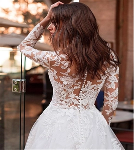 Détail des manches en dentelle et du dos boutonné sur une robe de mariée en tulle blanc