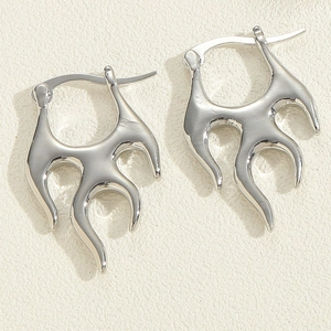 Macro shot of silver flame-shaped earrings with a polished metallic finish on textured paper