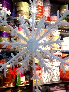 Close-up of white snowflake ornament with sparkling tinsel for Christmas tree decoration