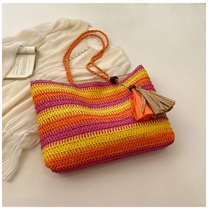 Detail of colorful woven straw tote bag with orange tassels and rainbow stripes