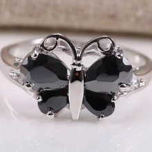 Macro shot of silver butterfly ring with black faceted stones on marble background