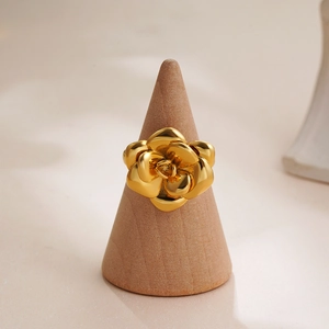 Elegant 18K gold camellia ring on wooden stand with polished flower petals