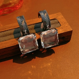 Détail de boucles d'oreilles en cristal carré avec crochets en métal argenté texturé en C