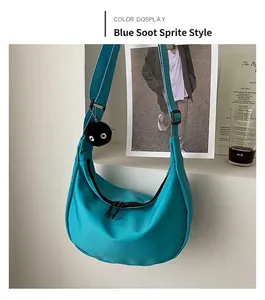 Detail of turquoise crescent crossbody bag with adjustable strap and plush charm