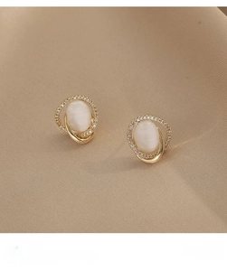 Macro detail of oval cat eye stone earrings with pavé zircon accents and gold metal trim