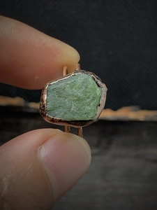 Detailed close-up of a vintage adjustable ring with an uncut green natural raw gemstone