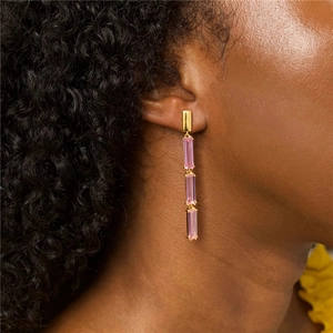Elegant gold drop earrings with triple emerald-cut pink stones worn by a model