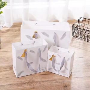 Three white feather gift bags with grey satin handles and festive Merry Christmas text