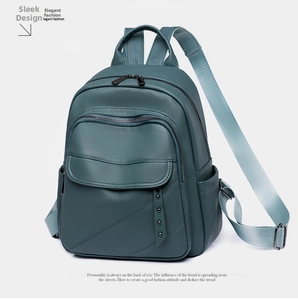 Detail view of dark green pebbled leather backpack featuring metal rivets and straps