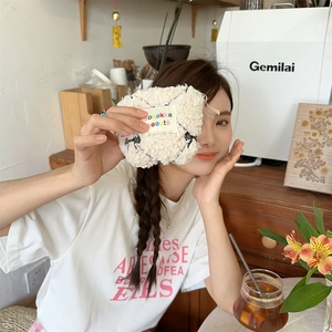 Close-up of white plush cosmetic pouch with black pattern and rainbow logo label