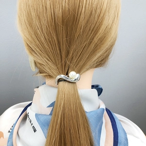 Elegant wave-shaped silver hair cuff with white pearl accent on mannequin's blonde hair