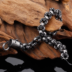 Close-up of gothic stainless steel skull link bracelet displayed on a wood branch