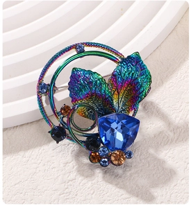 Macro shot of iridescent leaf brooch with blue crystal and cubic zirconia accents